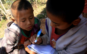 Two student sitting beside each other doing school work outdoors.